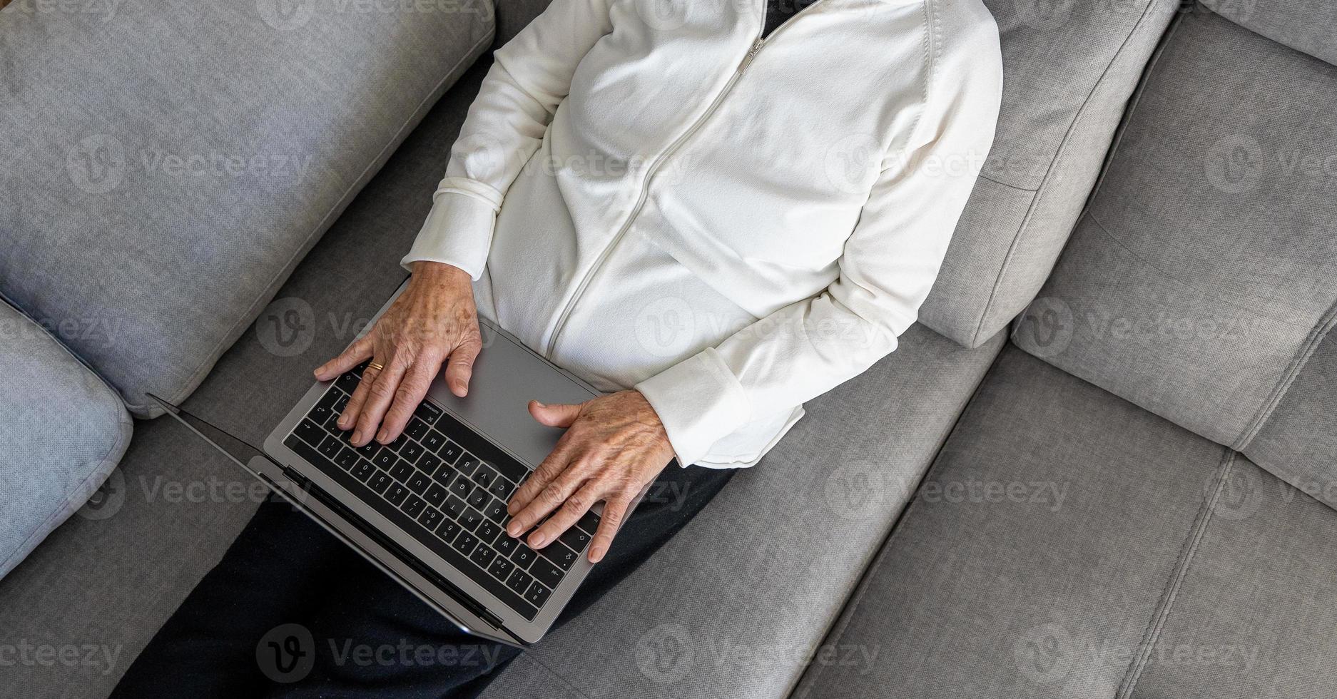 Calm senior woman browsing laptop in living room photo