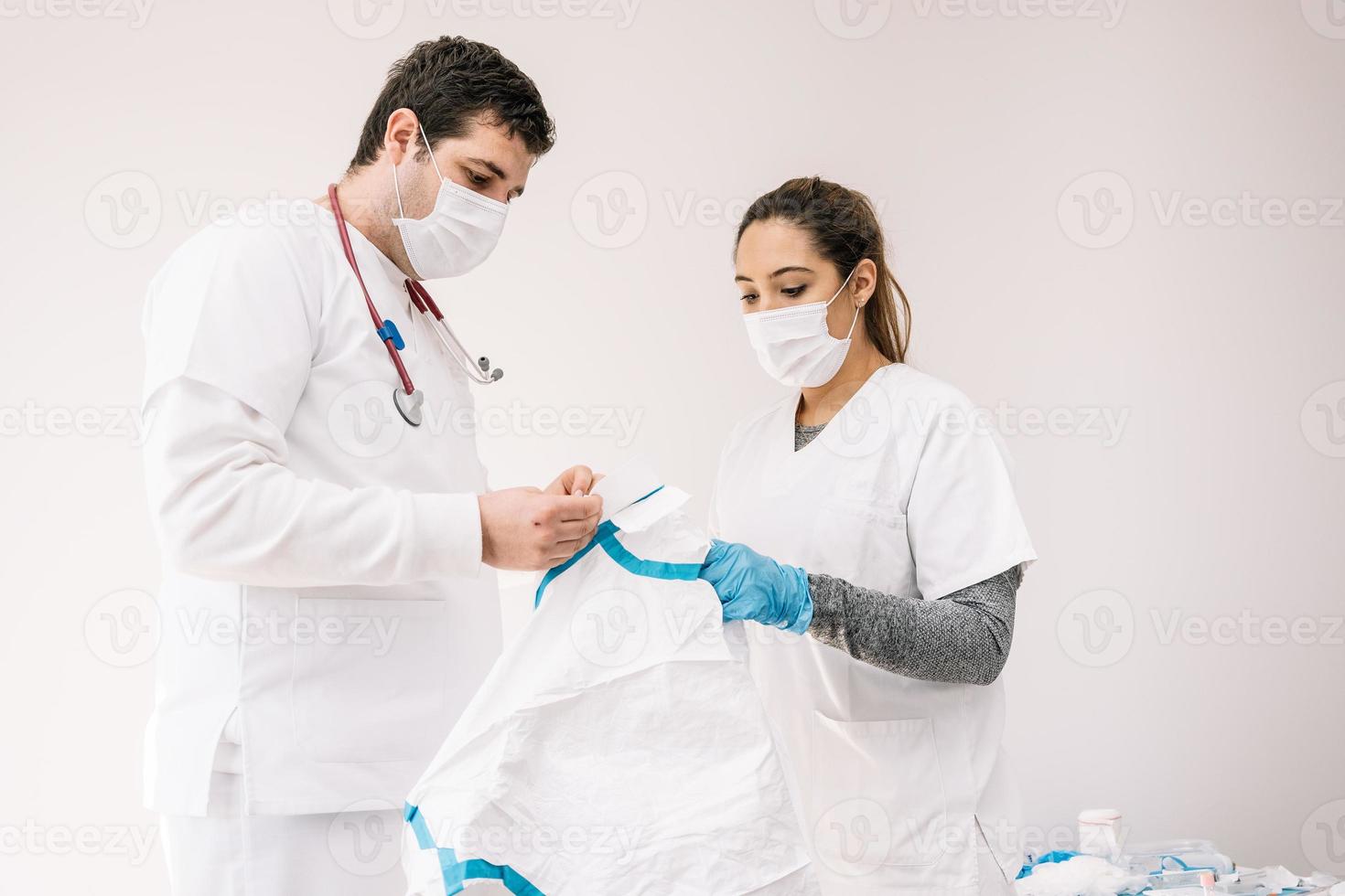 Médicos en máscaras de pie en la habitación con traje protector foto