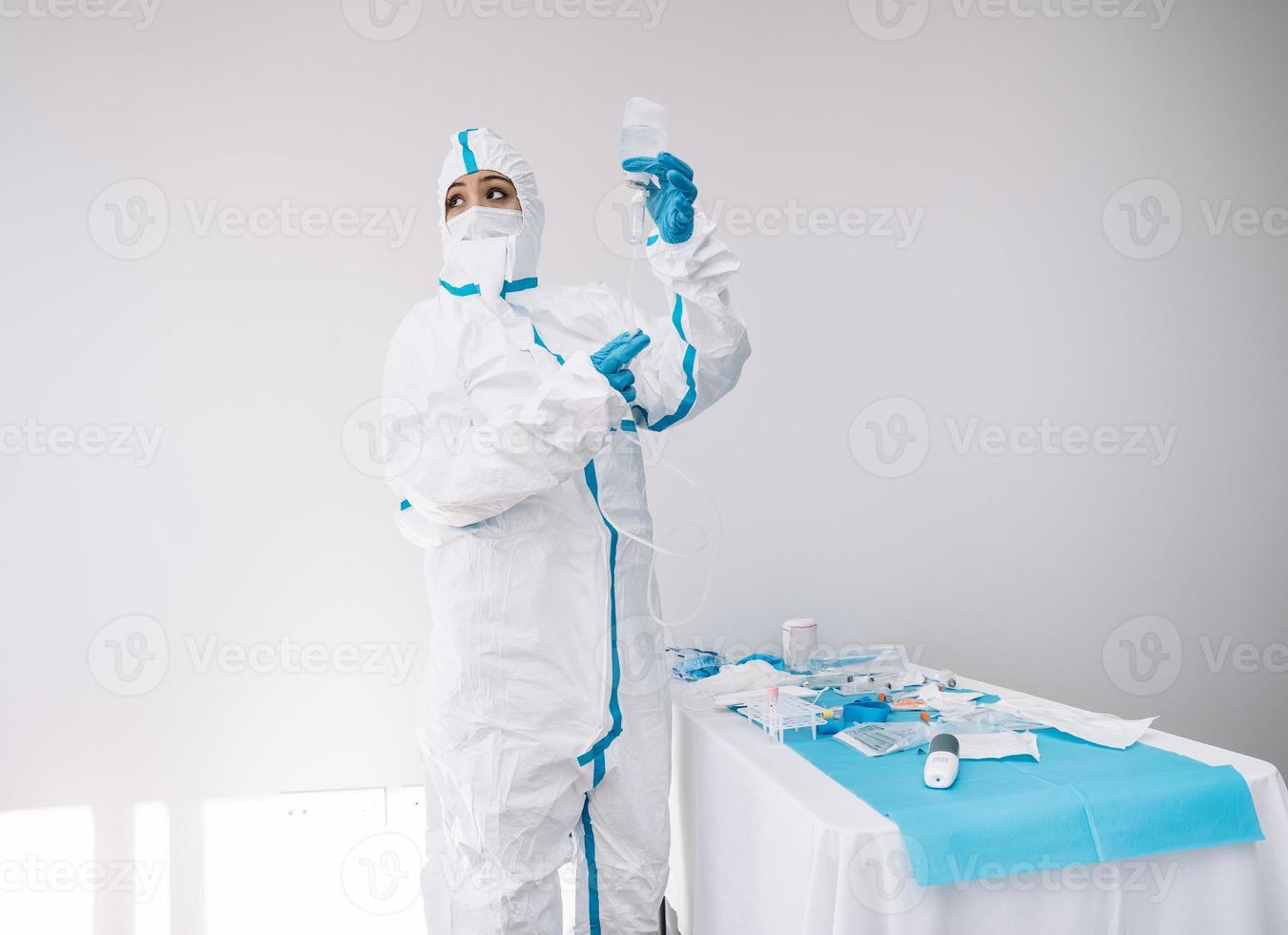 Doctor en máscara y traje protector con gotero en el hospital foto