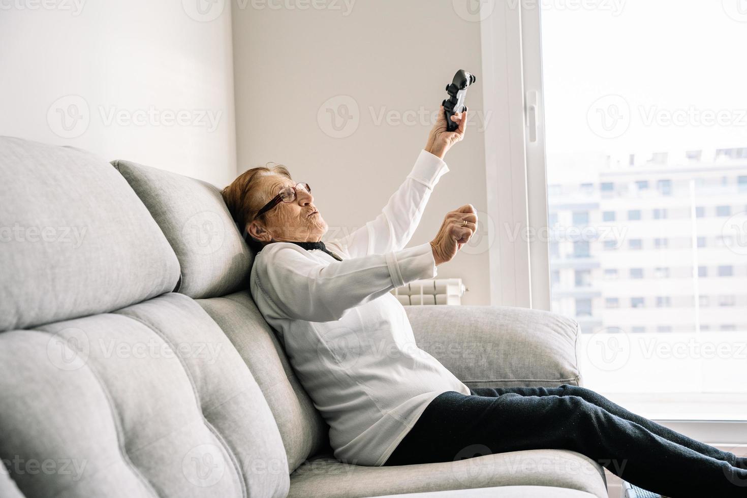 Excited elderly woman with controller playing video game photo