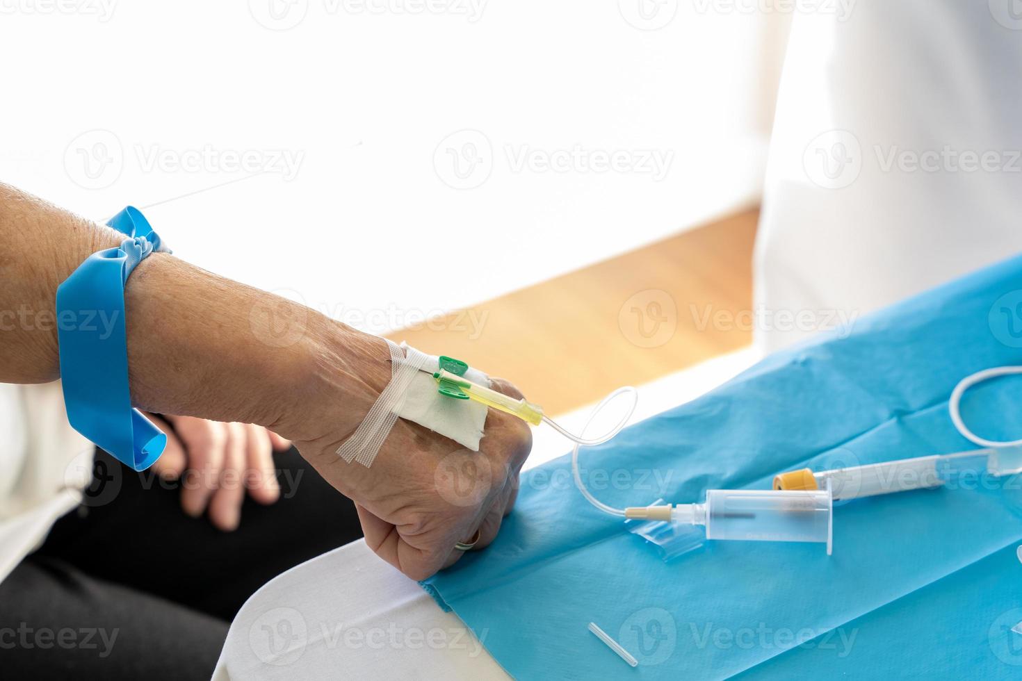 Crop medics taking blood from aged patient photo