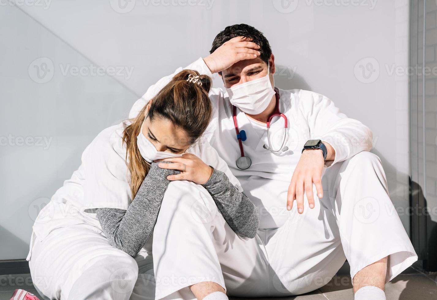 Médicos cansados durmiendo en el suelo en la terraza de la clínica juntos foto