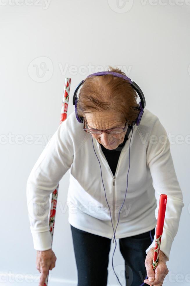 Smiling elderly woman cleaning floor and listening to music photo