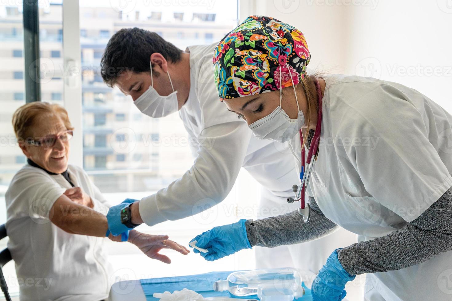 Doctors taking blood sample from senior patient photo