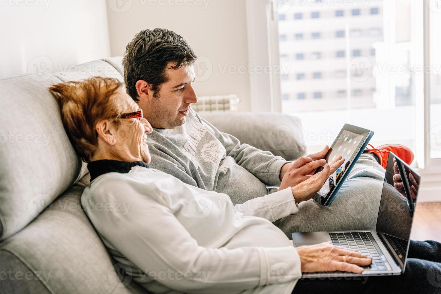 Cheerful man and senior woman using laptop together photo