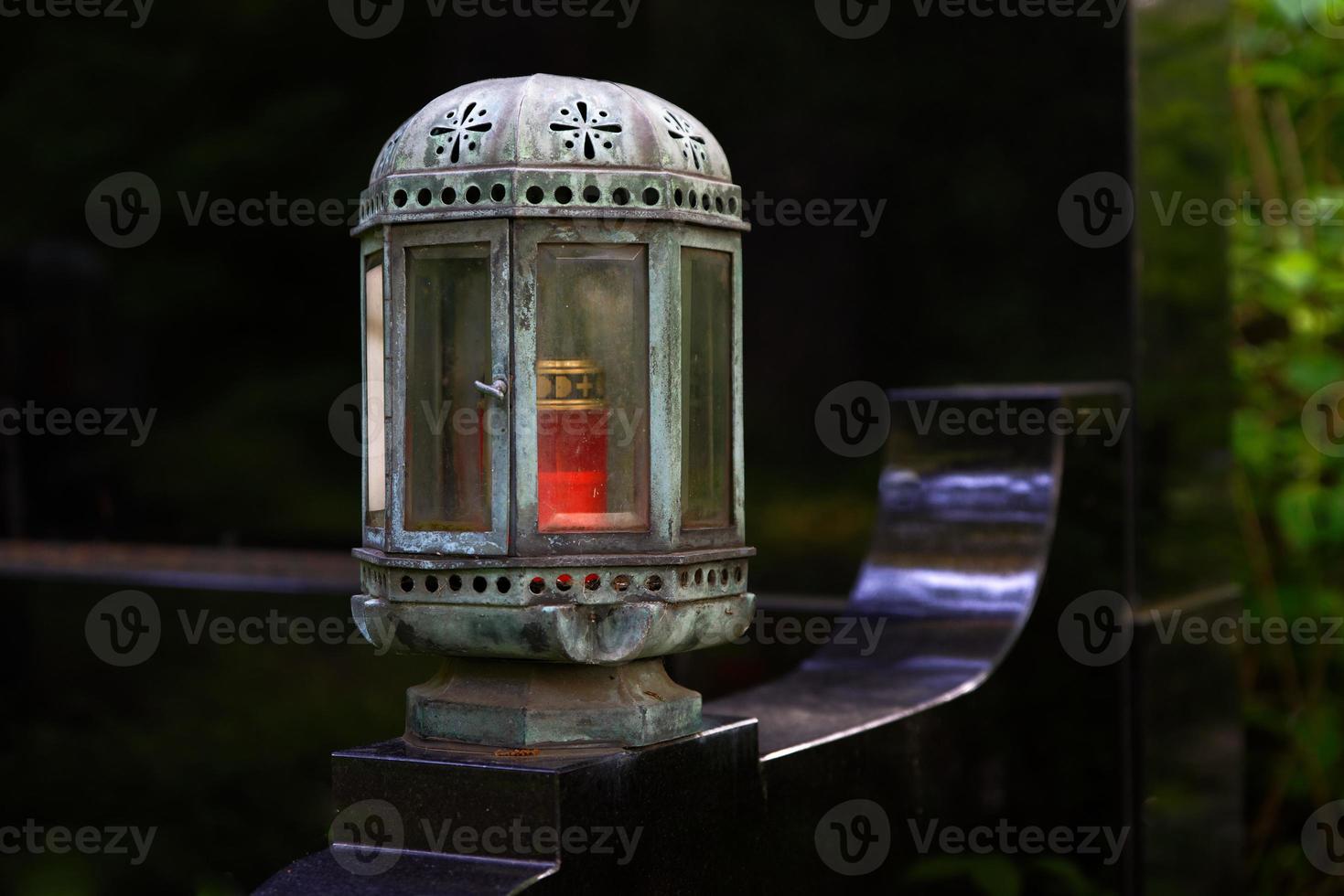 antique aged grave lantern on a distinguished grave with black gravestone photo