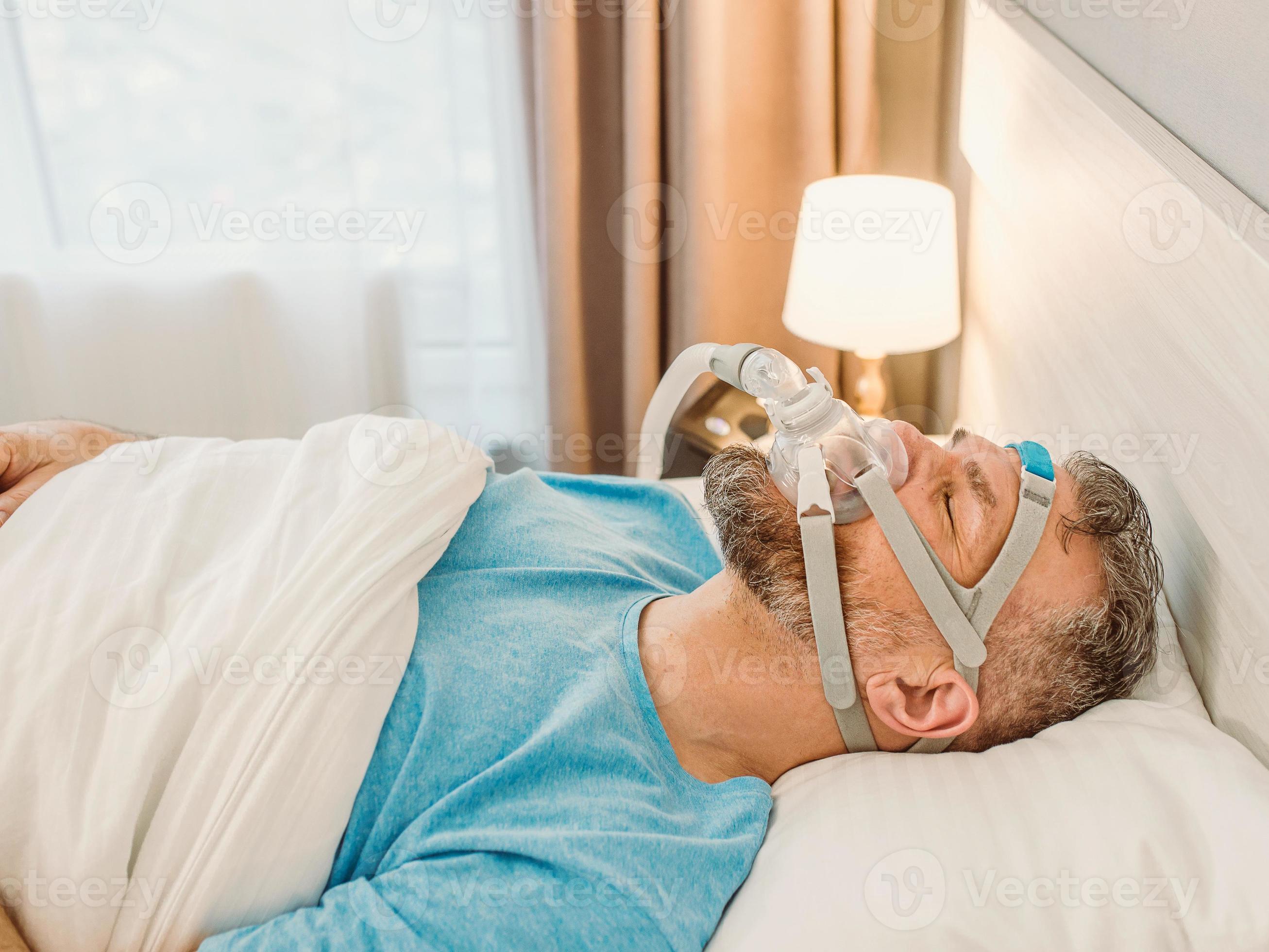 El hombre dormido con problemas respiratorios crónicos considera usar una máquina  cpap en la cama. cuidado de la salud, terapia de apnea obstructiva del sueño,  cpap, concepto de ronquidos 3606004 Foto de