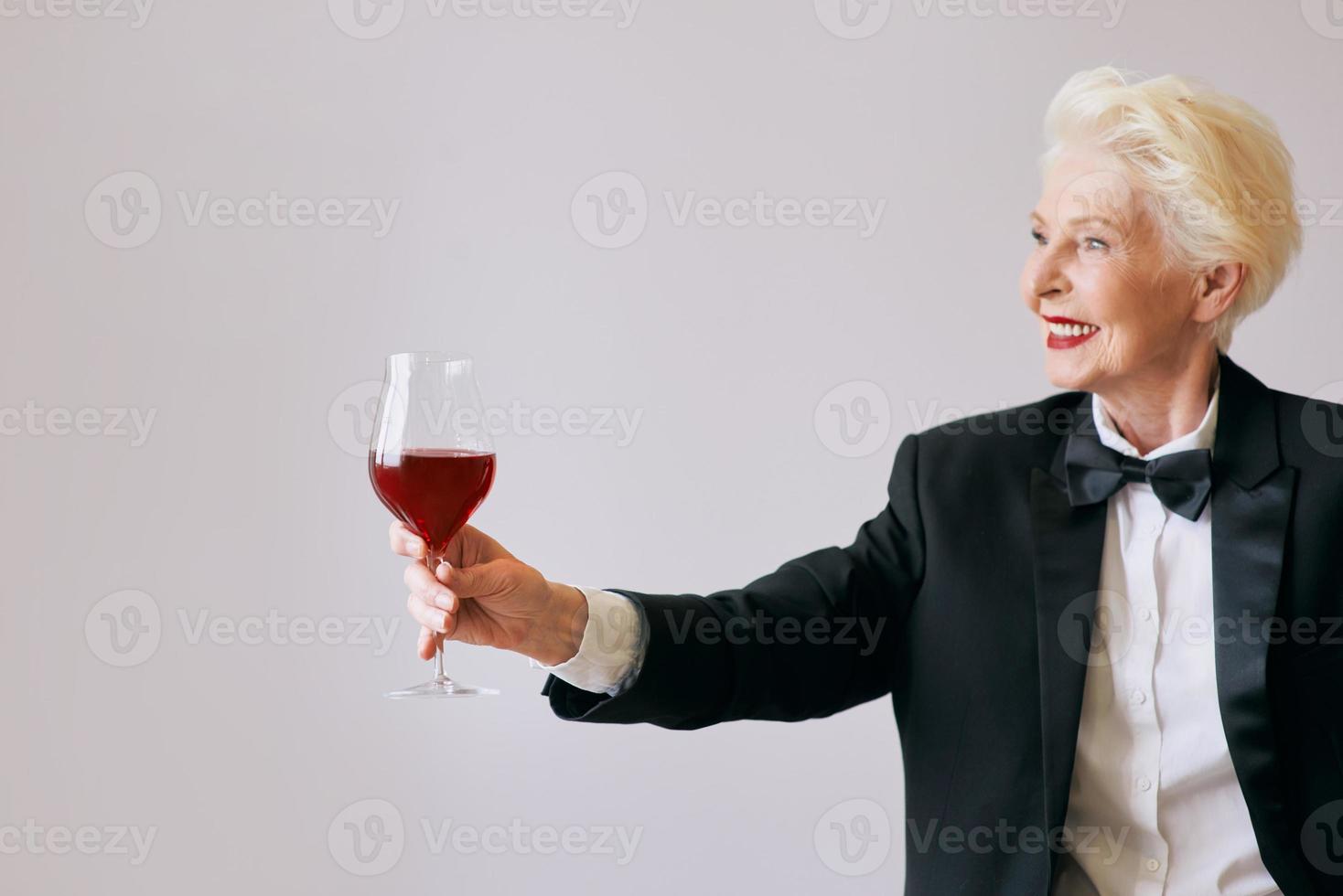 stylish senior sommelier woman in tuxedo with glass or red wine. Beverage, mature, style concept photo
