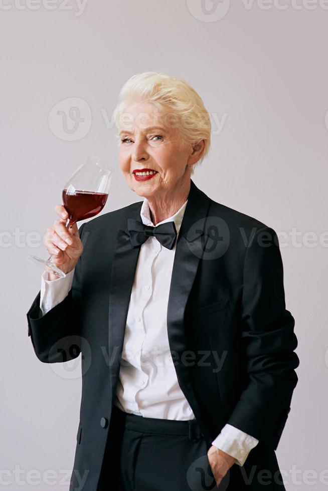 elegante mujer sommelier senior en esmoquin con copa o vino tinto. bebida, madura, concepto de estilo foto