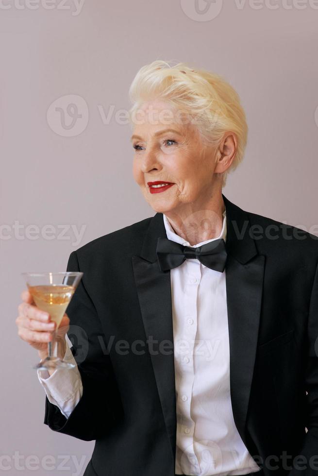 Mujer senior elegante sommelier madura en esmoquin con copa de vino espumoso. diversión, fiesta, estilo, estilo de vida, alcohol, concepto de celebración foto