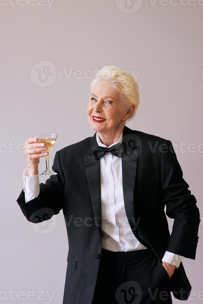 Mujer senior elegante sommelier madura en esmoquin con copa de vino espumoso. diversión, fiesta, estilo, estilo de vida, alcohol, concepto de celebración foto