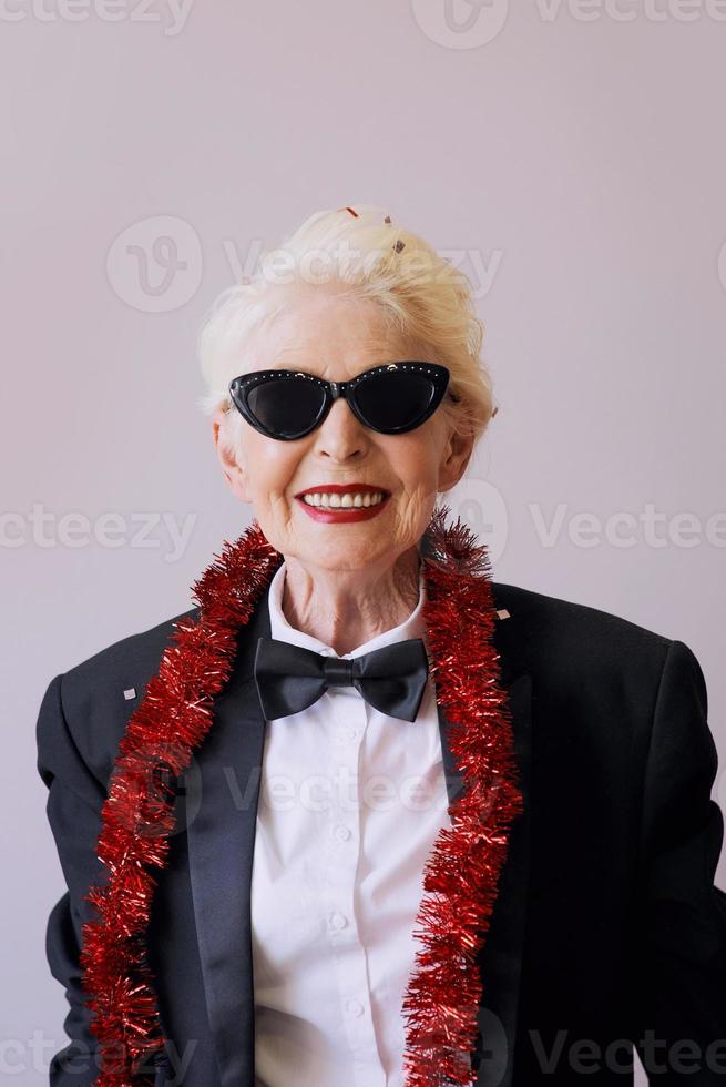 hermosa mujer senior madura con estilo en gafas de sol y esmoquin celebrando el año nuevo. diversión, fiesta, estilo, concepto de celebración foto