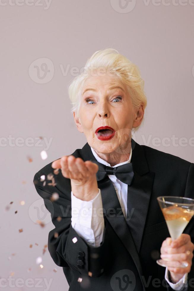 short hair stylish senior woman in tuxedo with glitter celebrating new year. Fun, lifestyle, style, age concept photo