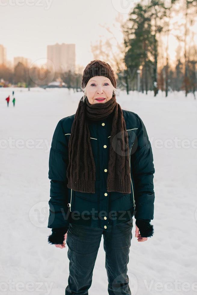 mujer mayor con sombrero y chaqueta deportiva bolas de nieve en el parque de invierno de nieve. invierno, edad, deporte, actividad, concepto de temporada foto