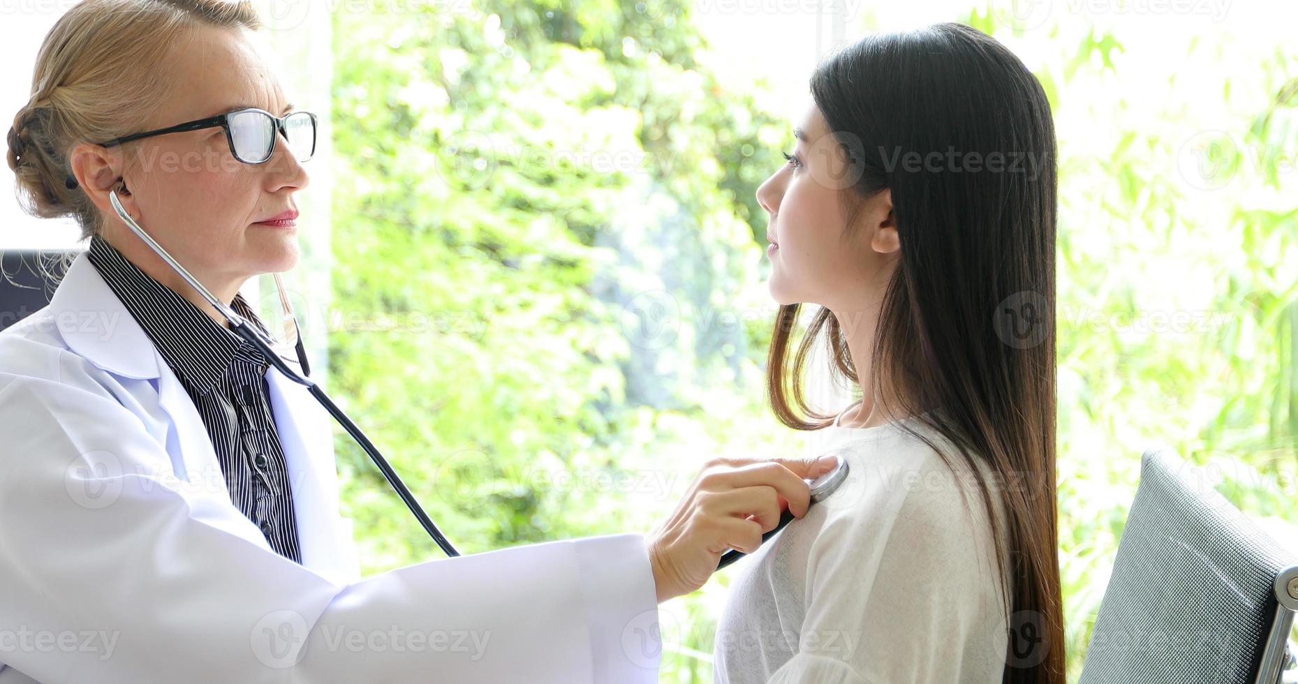 Doctor using stethoscope for examining patient  in his office at Hospitals photo