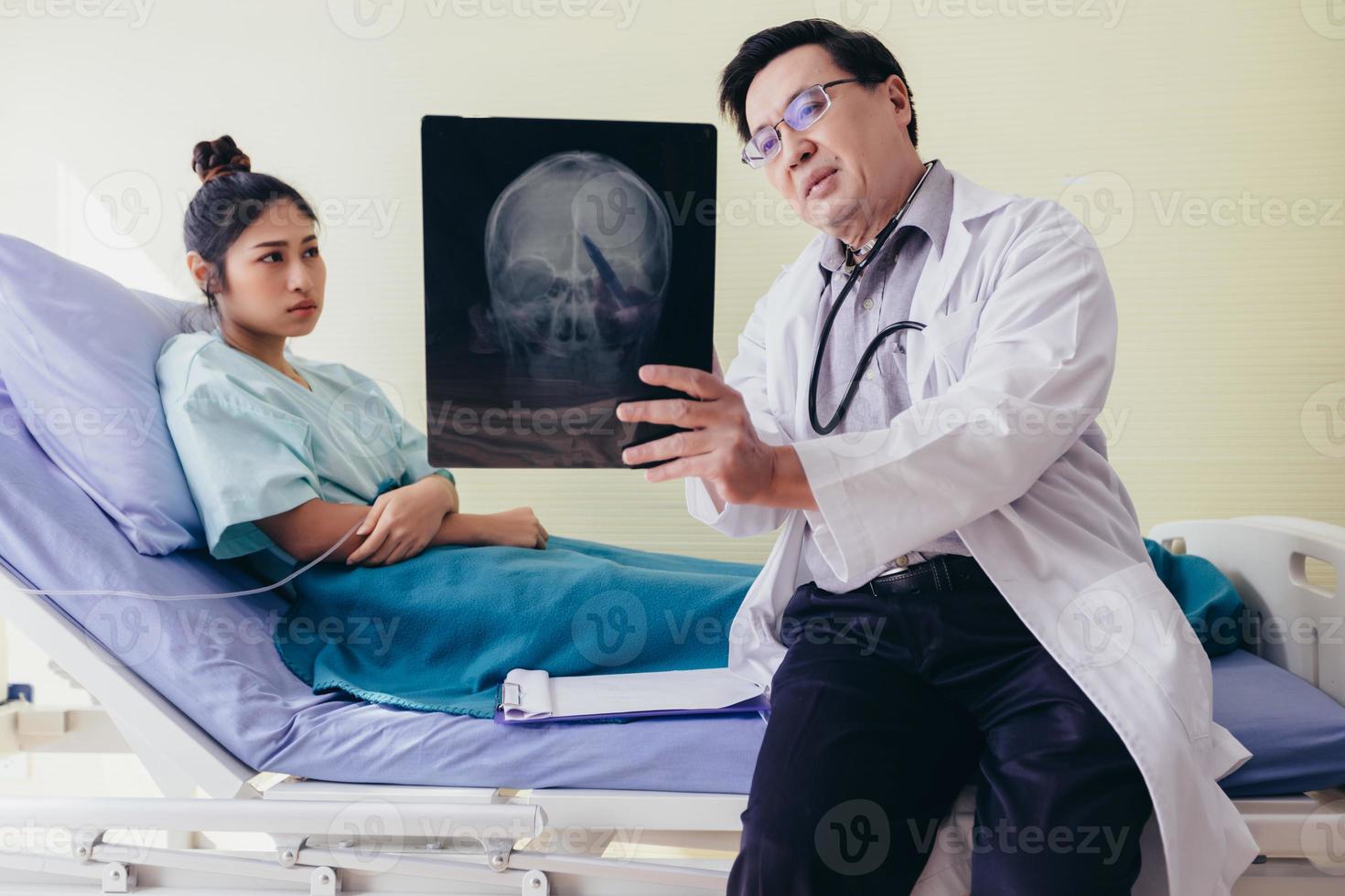 el médico está explicando los resultados de la radiografía del cerebro a una paciente acostada en la cama de un hospital foto