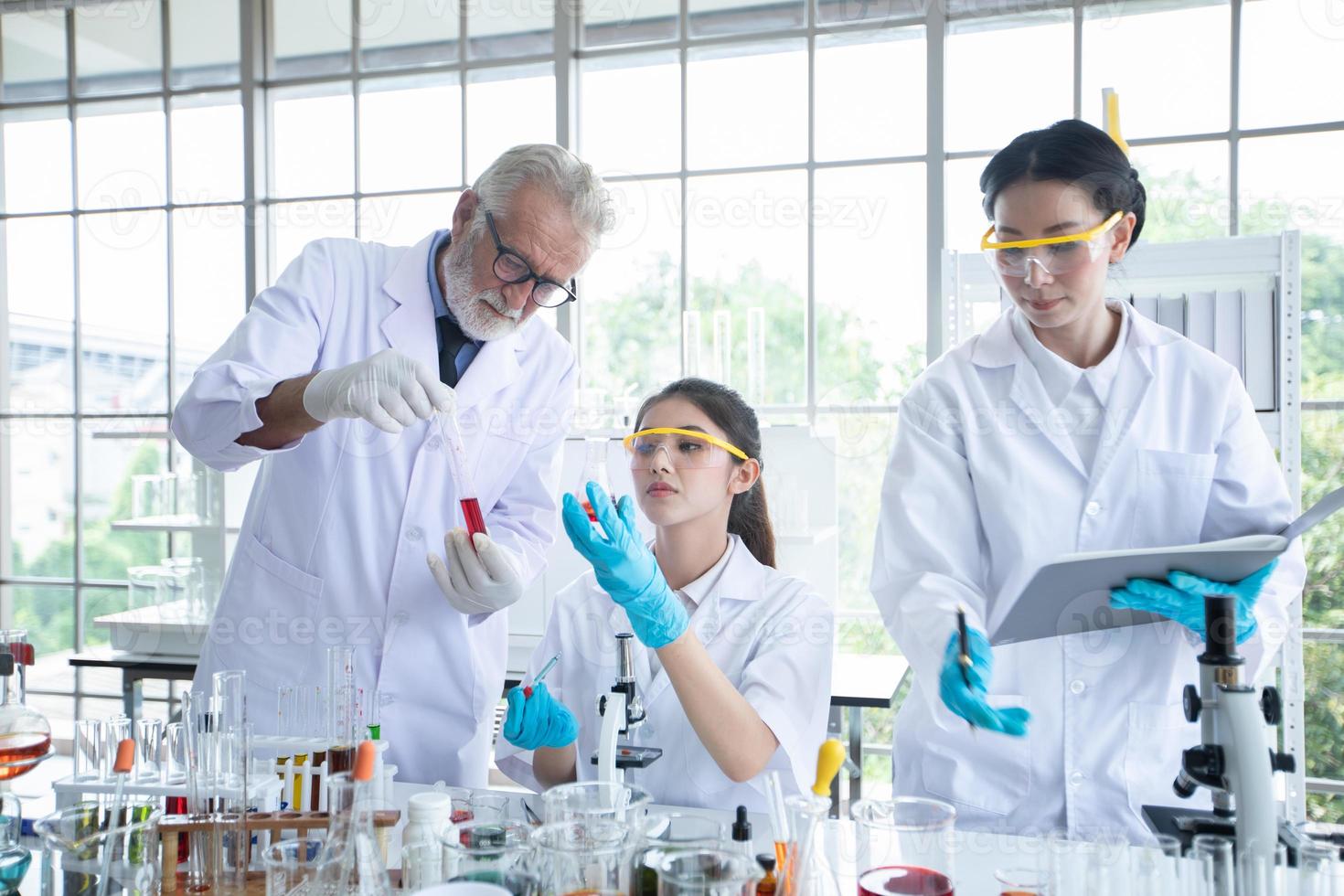 La investigación médica y los científicos están trabajando con un microscopio y una tableta y tubos de ensayo, micropipetas y resultados de análisis en un laboratorio. foto