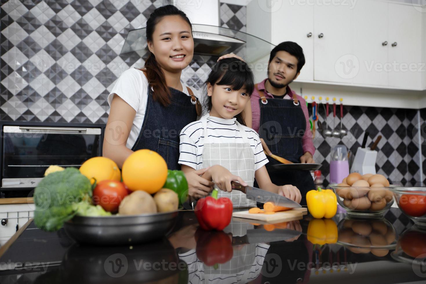 Happy Family have Dad, Mom and their little daughter Cooking Together in the Kitchen photo