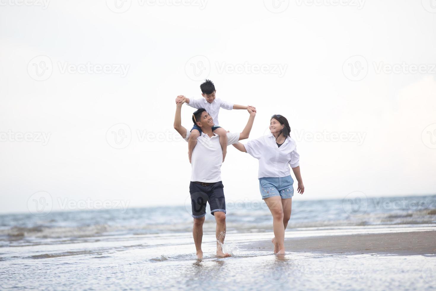 padres activos y personas actividad al aire libre en vacaciones de verano y vacaciones con niños.Familia feliz e hijo caminan con la diversión del mar al atardecer en la playa de arena. foto