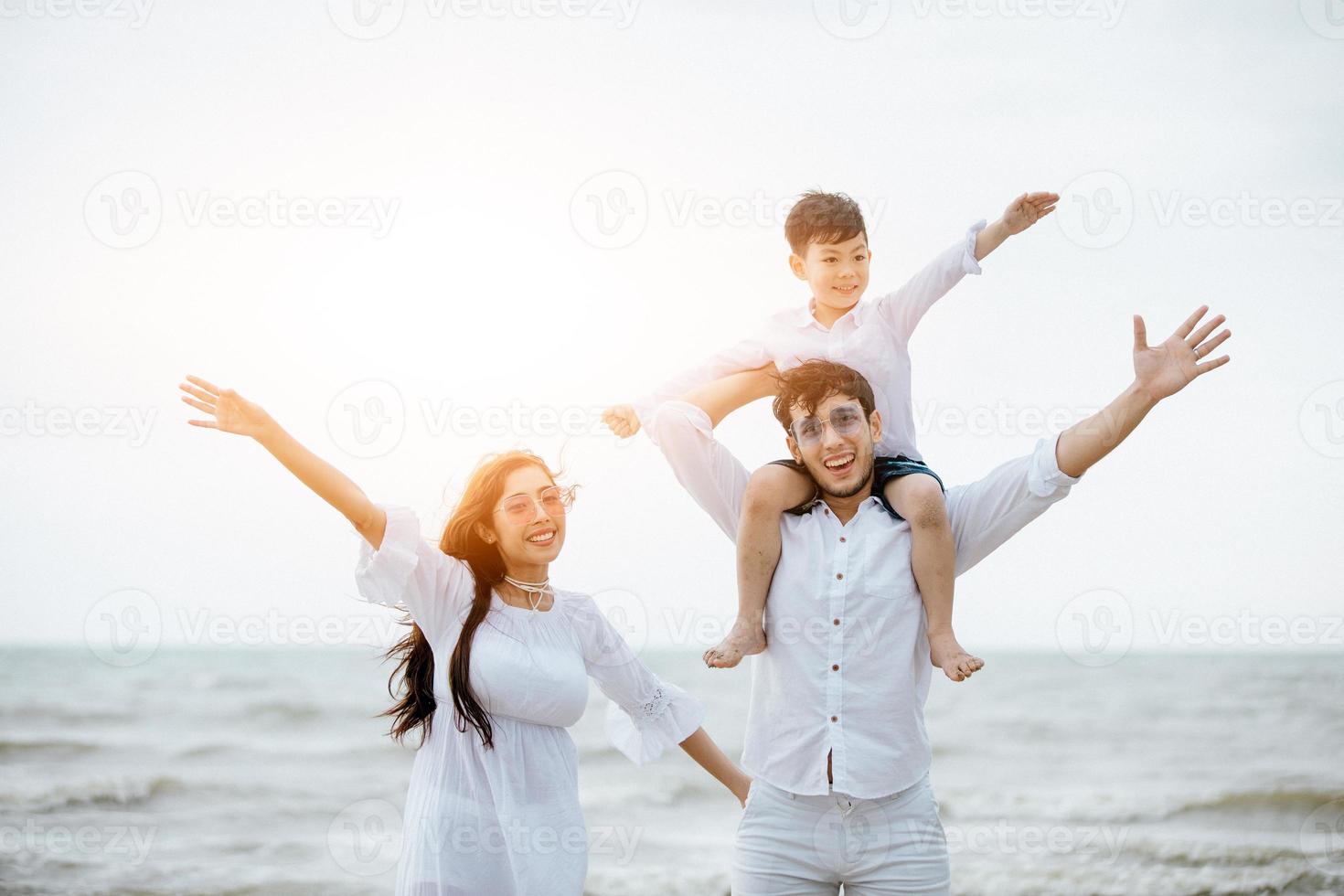 padres activos y personas actividad al aire libre en vacaciones de verano y vacaciones con niños.Familia feliz e hijo caminan con la diversión del mar al atardecer en la playa de arena. foto