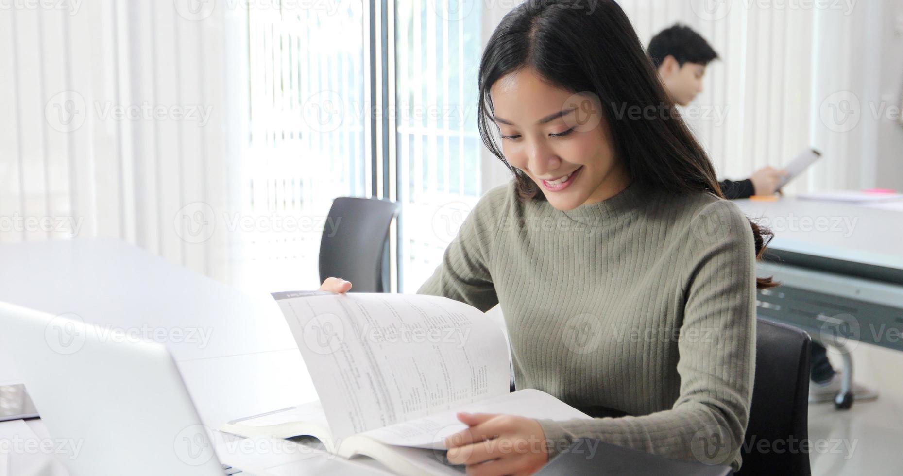 Las estudiantes asiáticas sonríen y leen un libro y usan el cuaderno para ayudar a compartir ideas en el trabajo y el proyecto. y también revisar el libro antes del examen foto