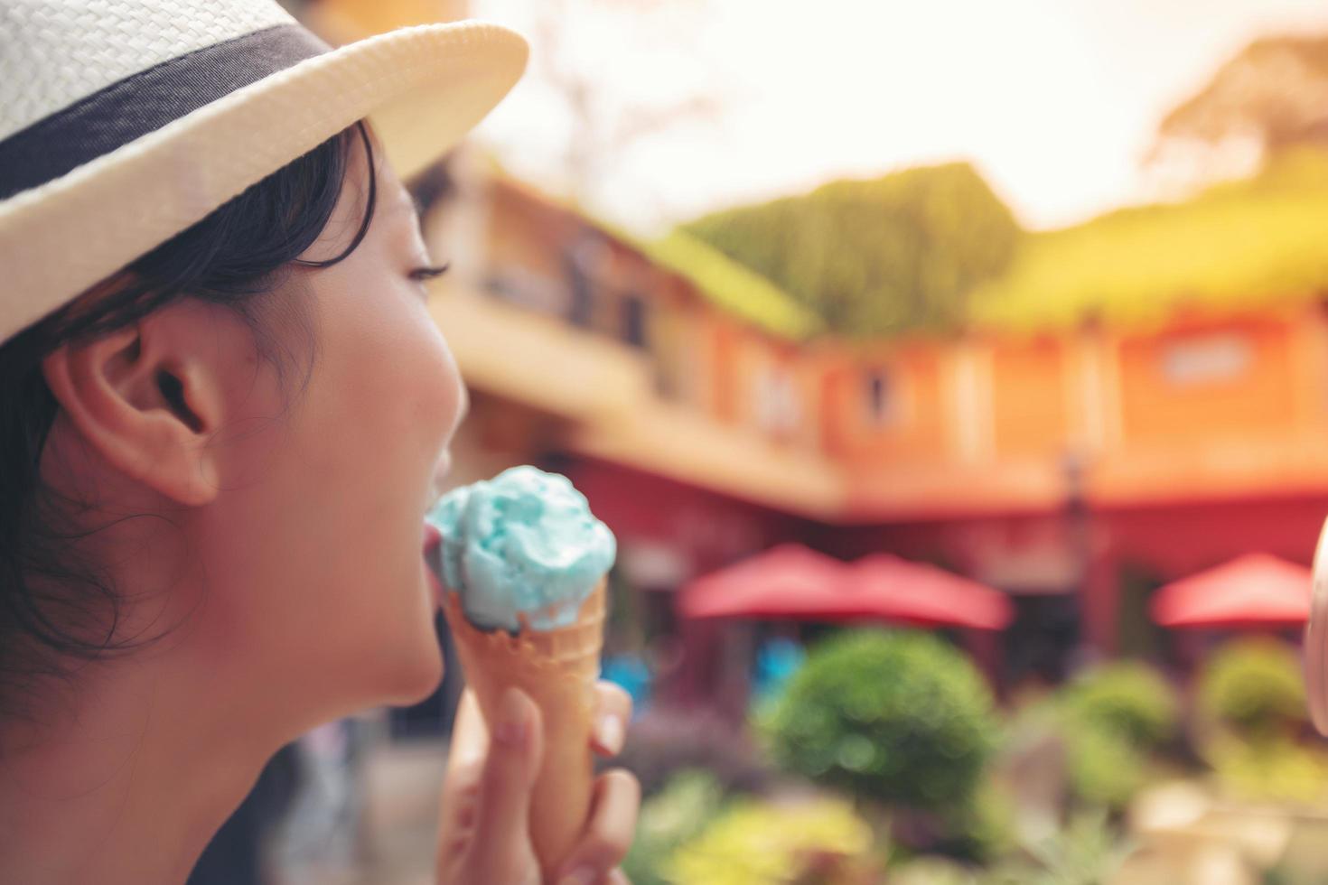 Borrosa de hermosa mujer sosteniendo y comiendo helado en las vacaciones de verano foto