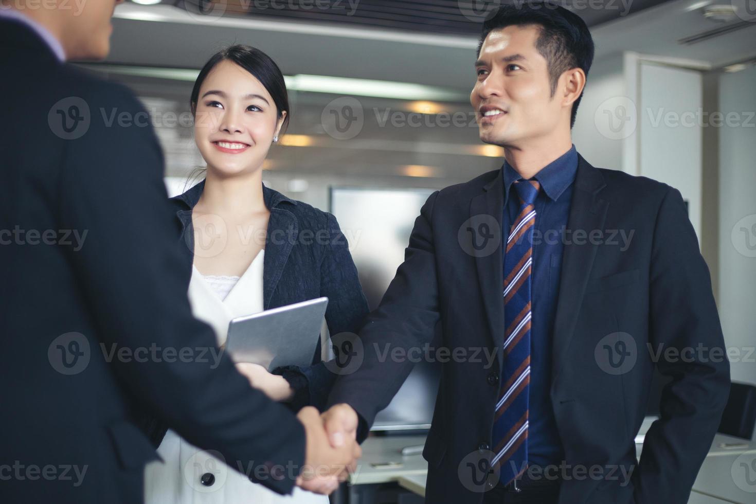 Business people shaking hands and smiling their agreement to sign contract and finishing up a meeting photo