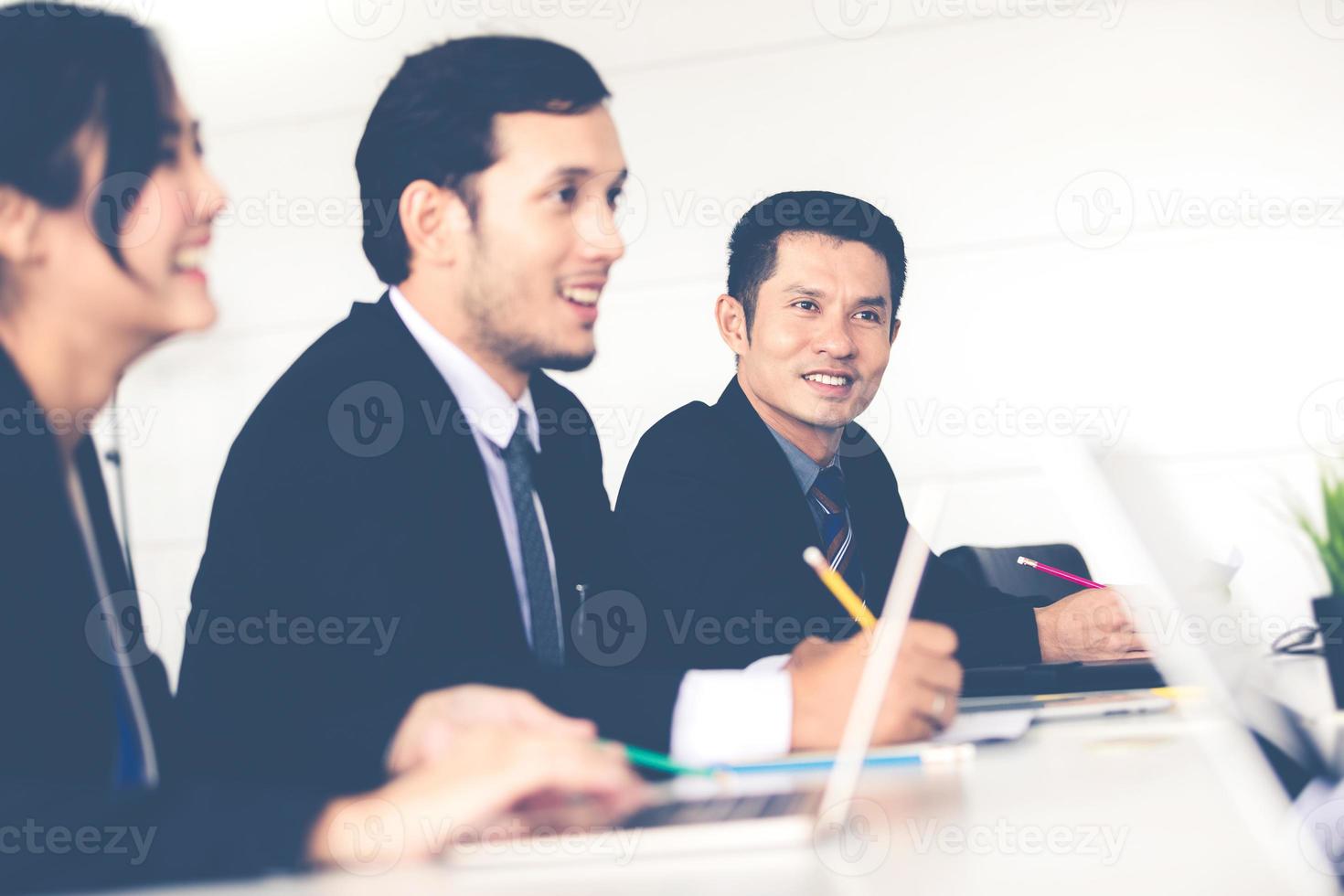 Hombres de negocios asiáticos y grupo que usan el cuaderno para socios comerciales que discuten documentos e ideas en reuniones y mujeres de negocios sonriendo felices por trabajar foto