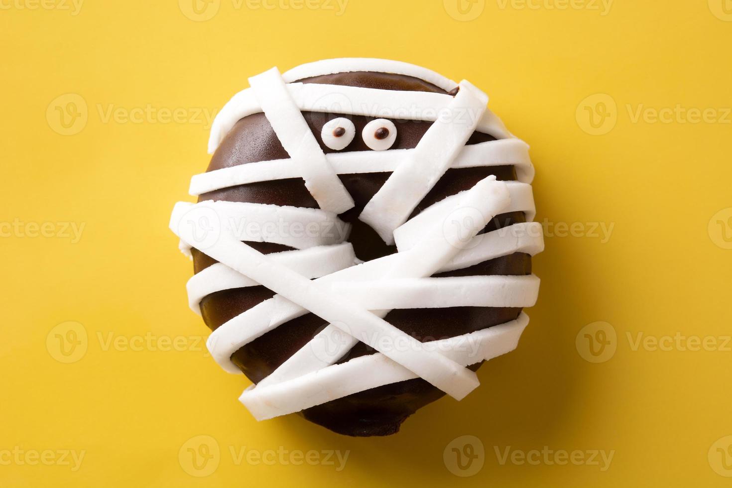 Mummy monster donut for Halloween party on yellow background photo