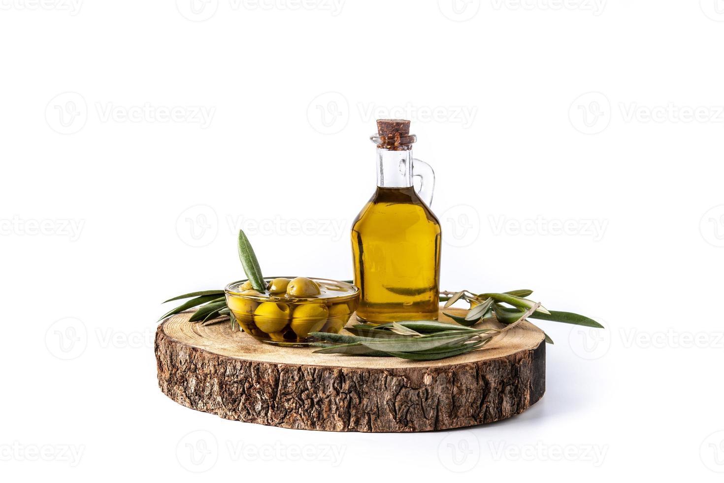 Aceite de oliva virgen con aceitunas verdes en recipiente de cristal aislado sobre fondo blanco. foto