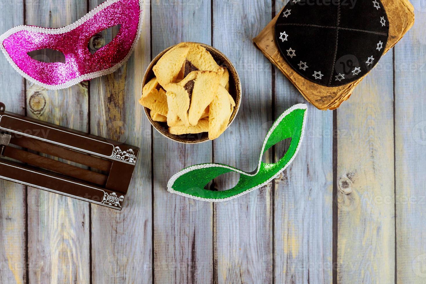 Jewish carnival Purim celebration on hamantaschen cookies, noisemaker and mask photo