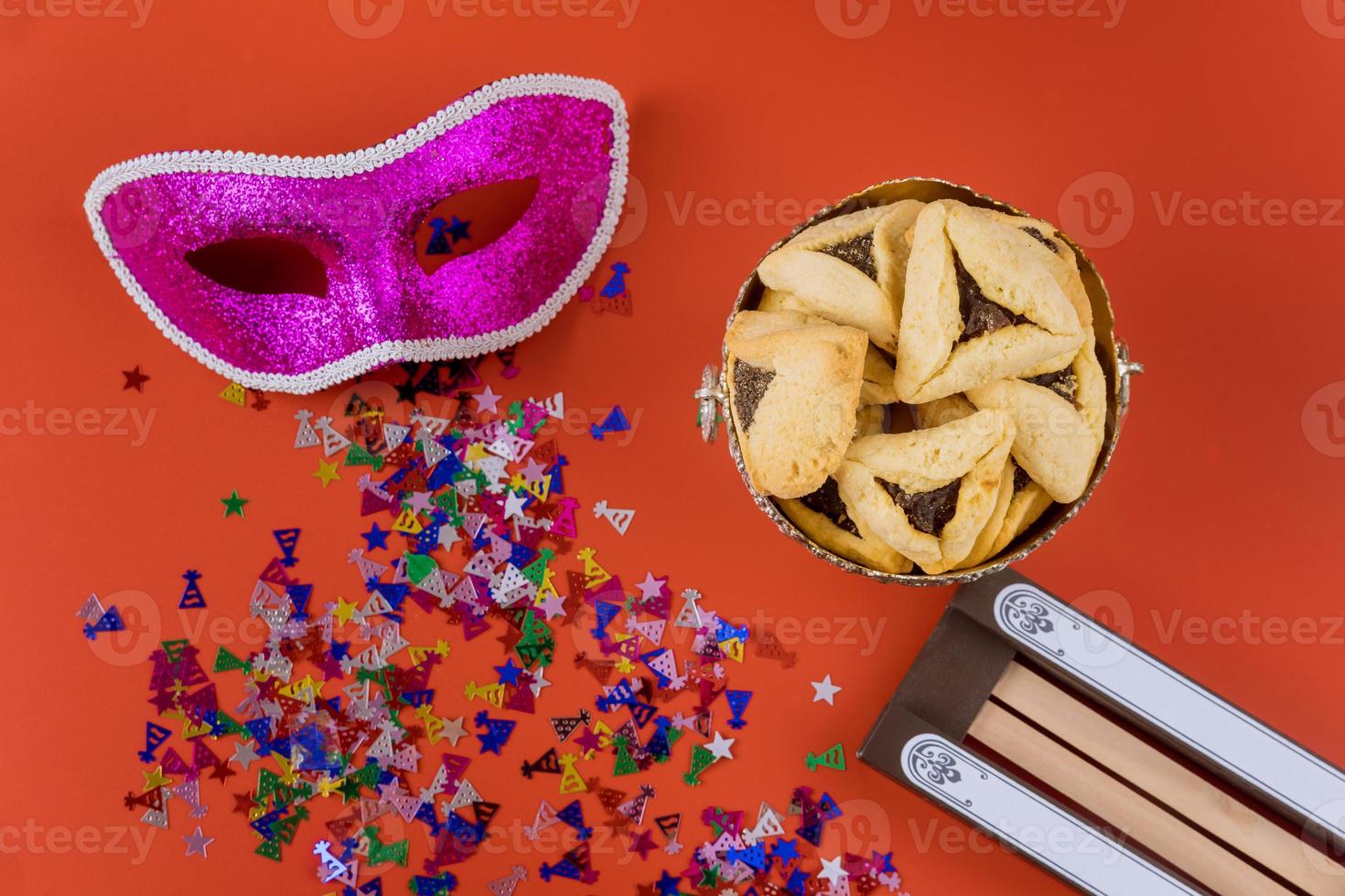 Purim Jewish carnival celebration on hamantaschen cookies, noisemaker and mask photo