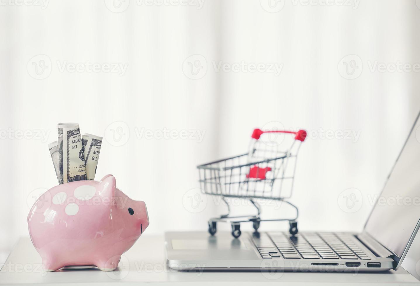 shopping cart and piggy bank with laptop on the desk photo