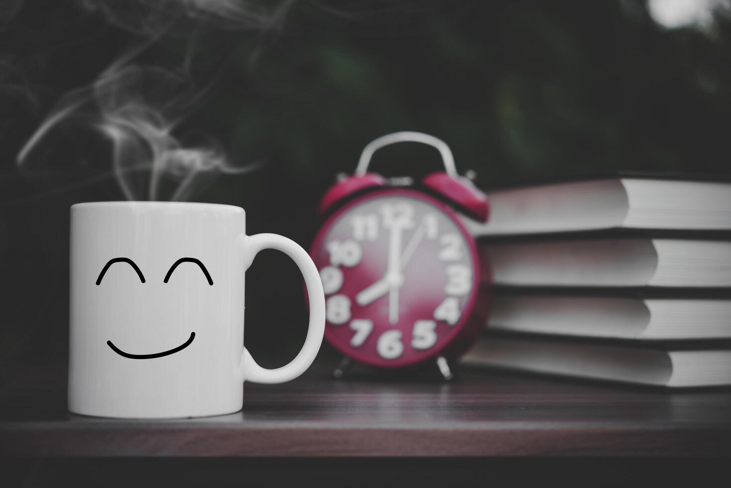 book with vintage alarm clock and coffee cup on wood table. photo