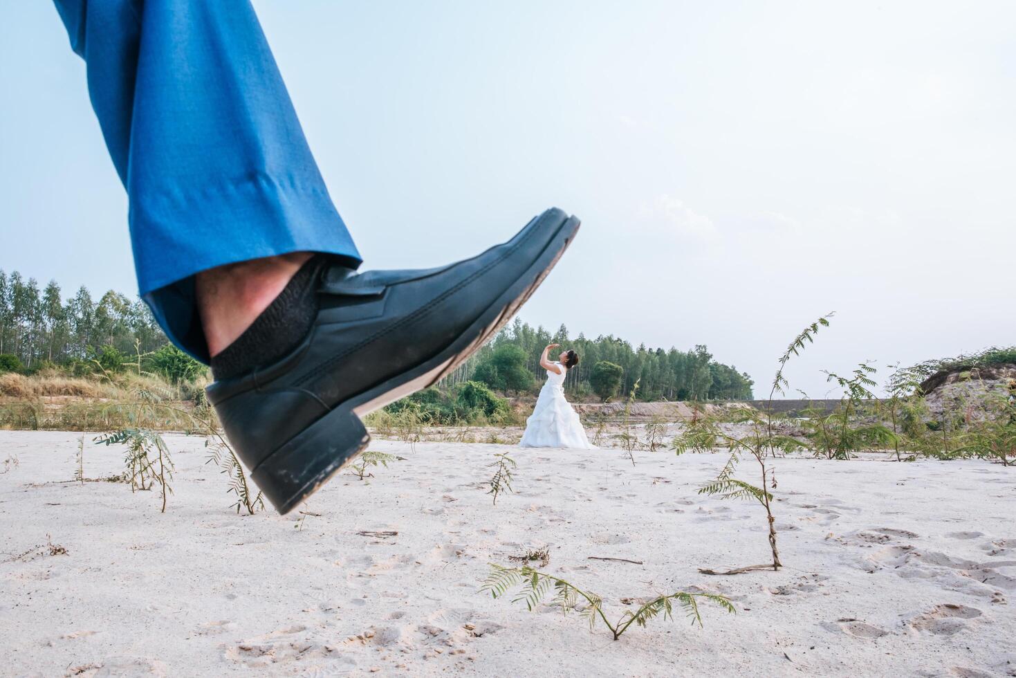 Funny Asian bride and Caucasian groom Posting joke with feet on the top photo