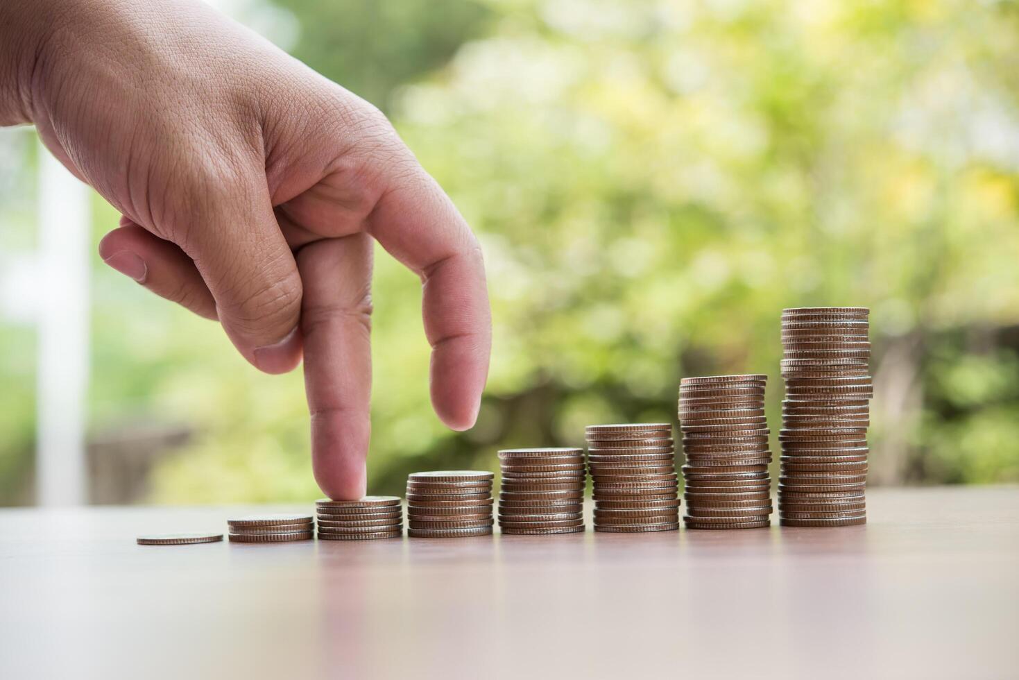 dedos caminando sobre la pila de monedas o pila de dinero foto