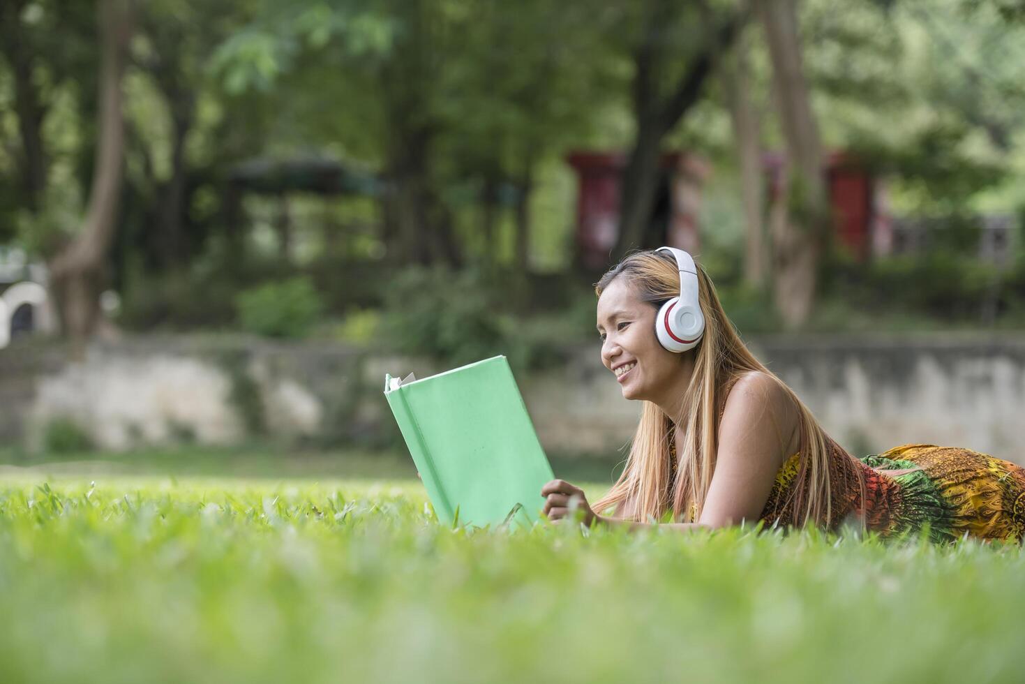 Asian woman listening favorite music on headphones and reading a book. Happy time and relax. photo