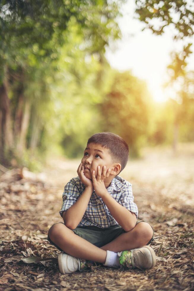 niño feliz sentado y pensando solo en el parque foto