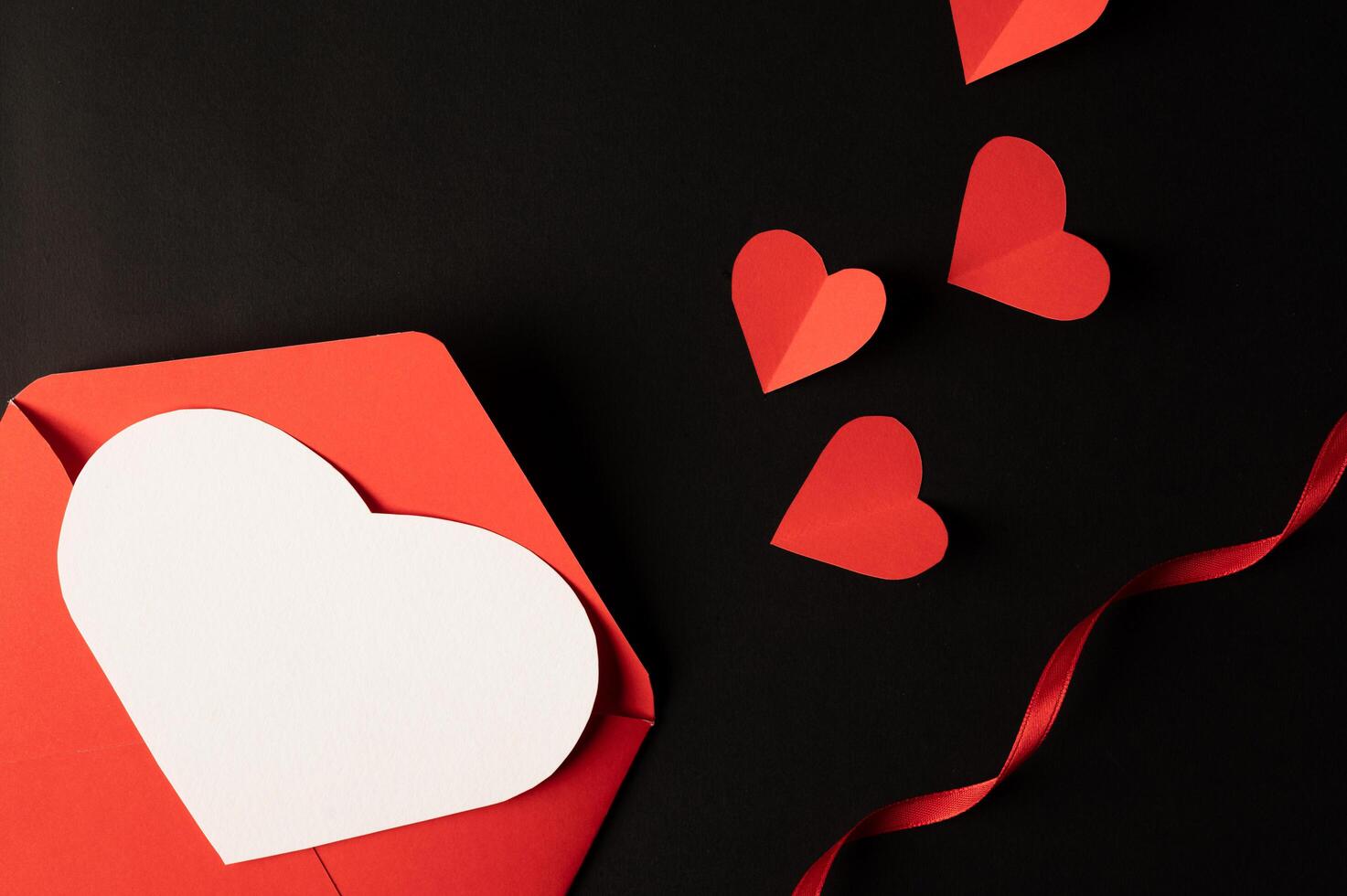White hearts and red hearts made of paper are placed on a black background. photo