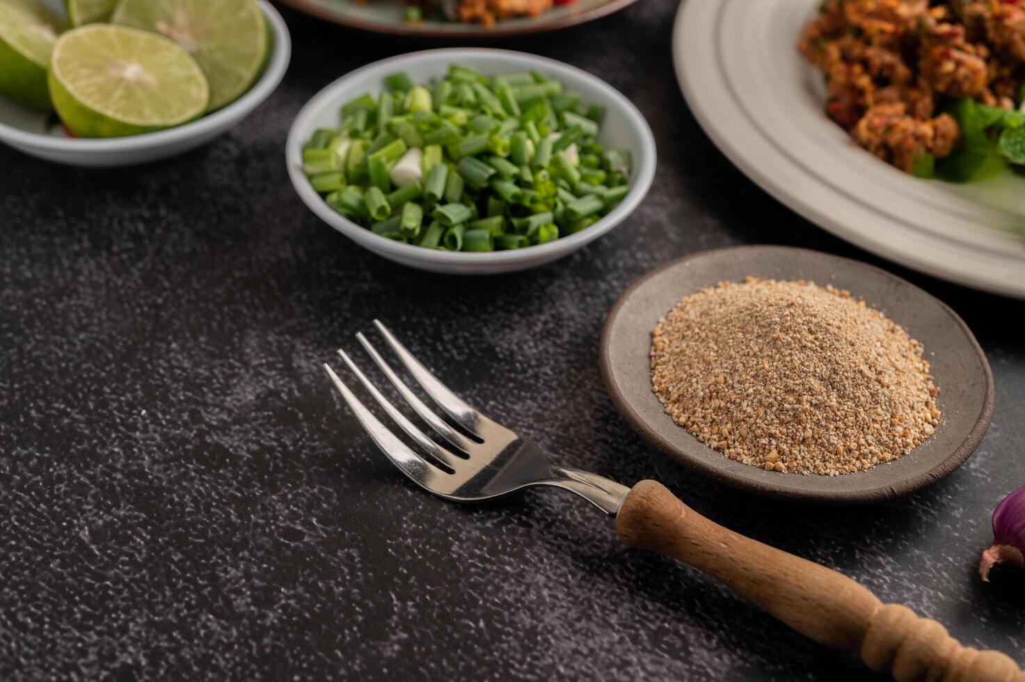 Fork, roasted rice, chopped scallions and lime cut in half on a black cement floor. photo