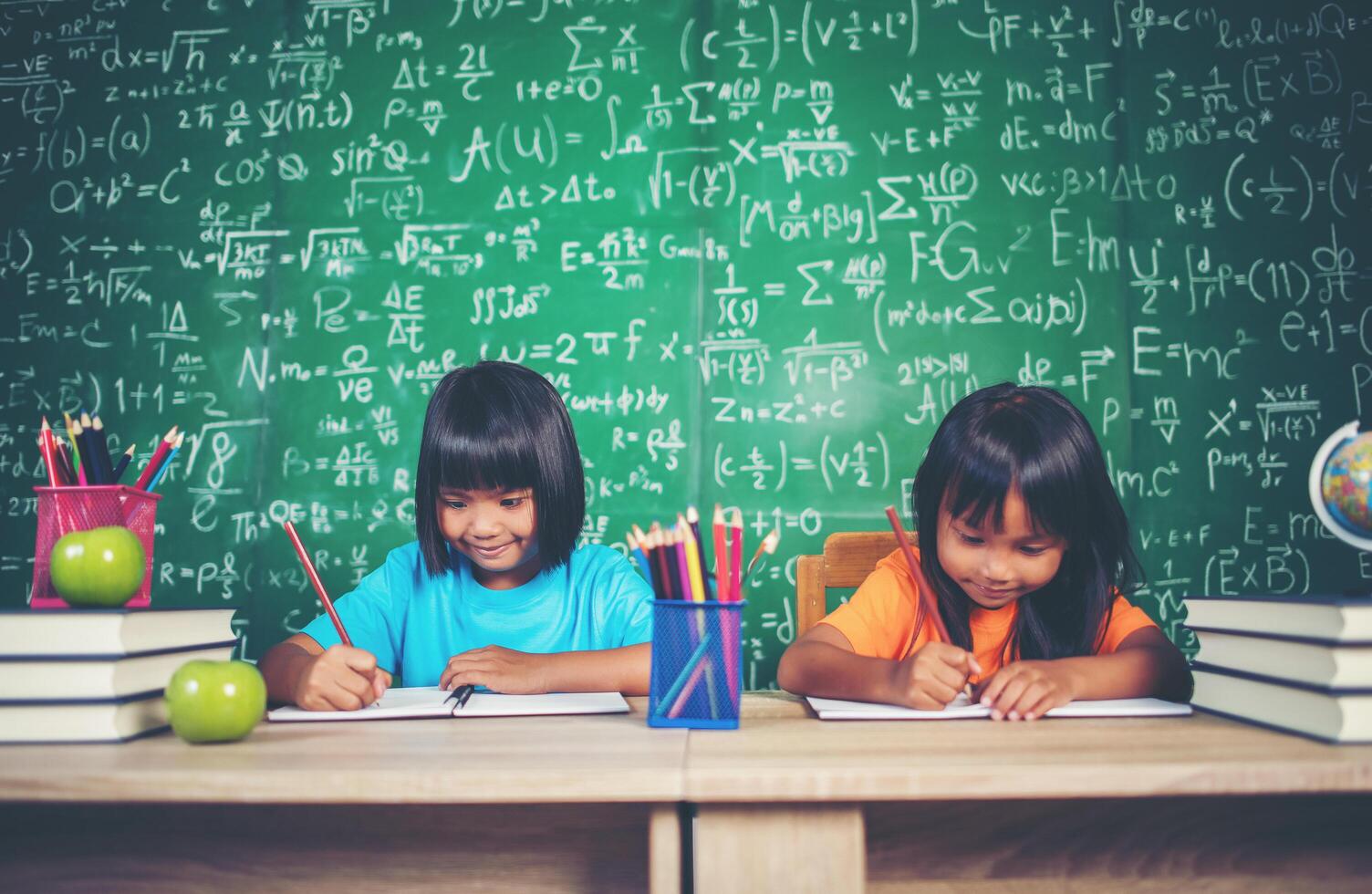 Two girl with crayon drawing at lesson in the classroom photo