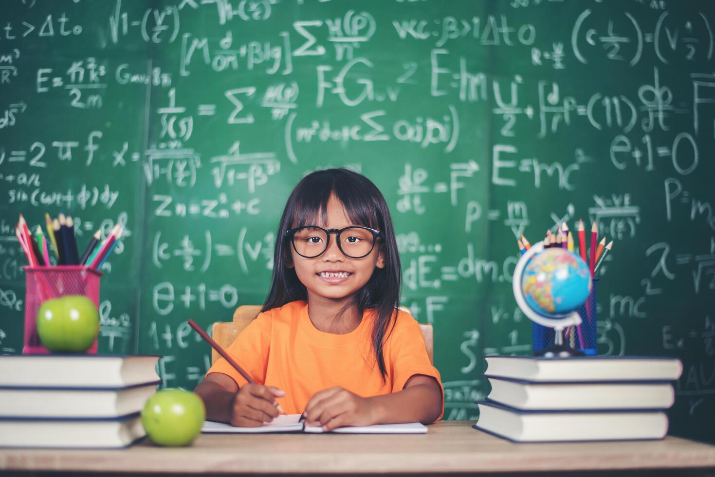 girl with crayon drawing at lesson in the classroom photo