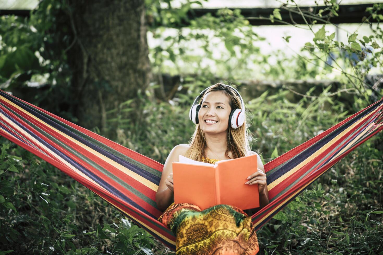 Beautiful happy young woman with headphones listening to music and reading a book photo