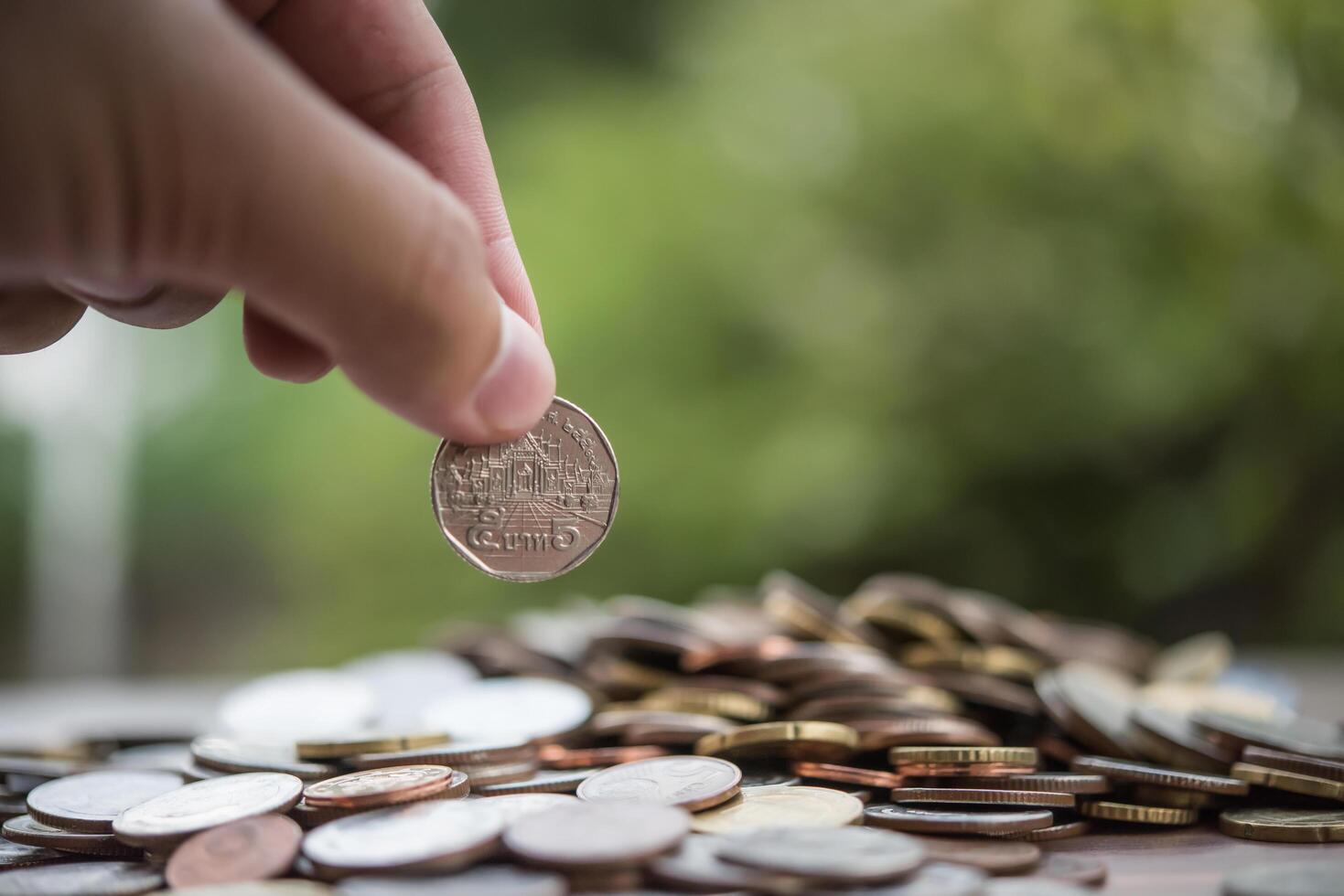 concepto de ahorro de dinero. mano poniendo dinero pila de monedas foto