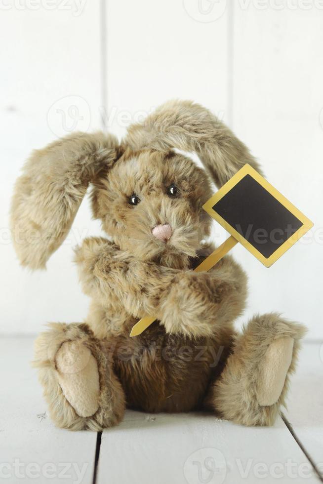 Oso de peluche como conejito casero sobre fondo blanco de madera foto