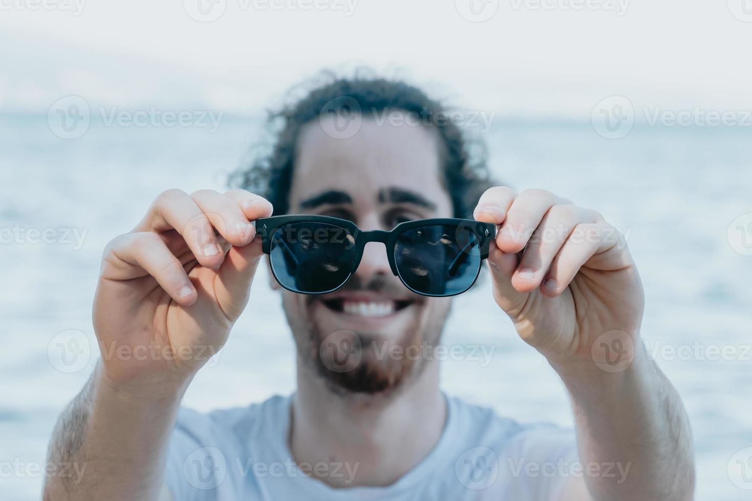 Hombre joven usa gafas de sol sonriendo mucho mientras las toca, concepto de gafas de viajes, espacio de copia 3617182 Foto de stock en Vecteezy