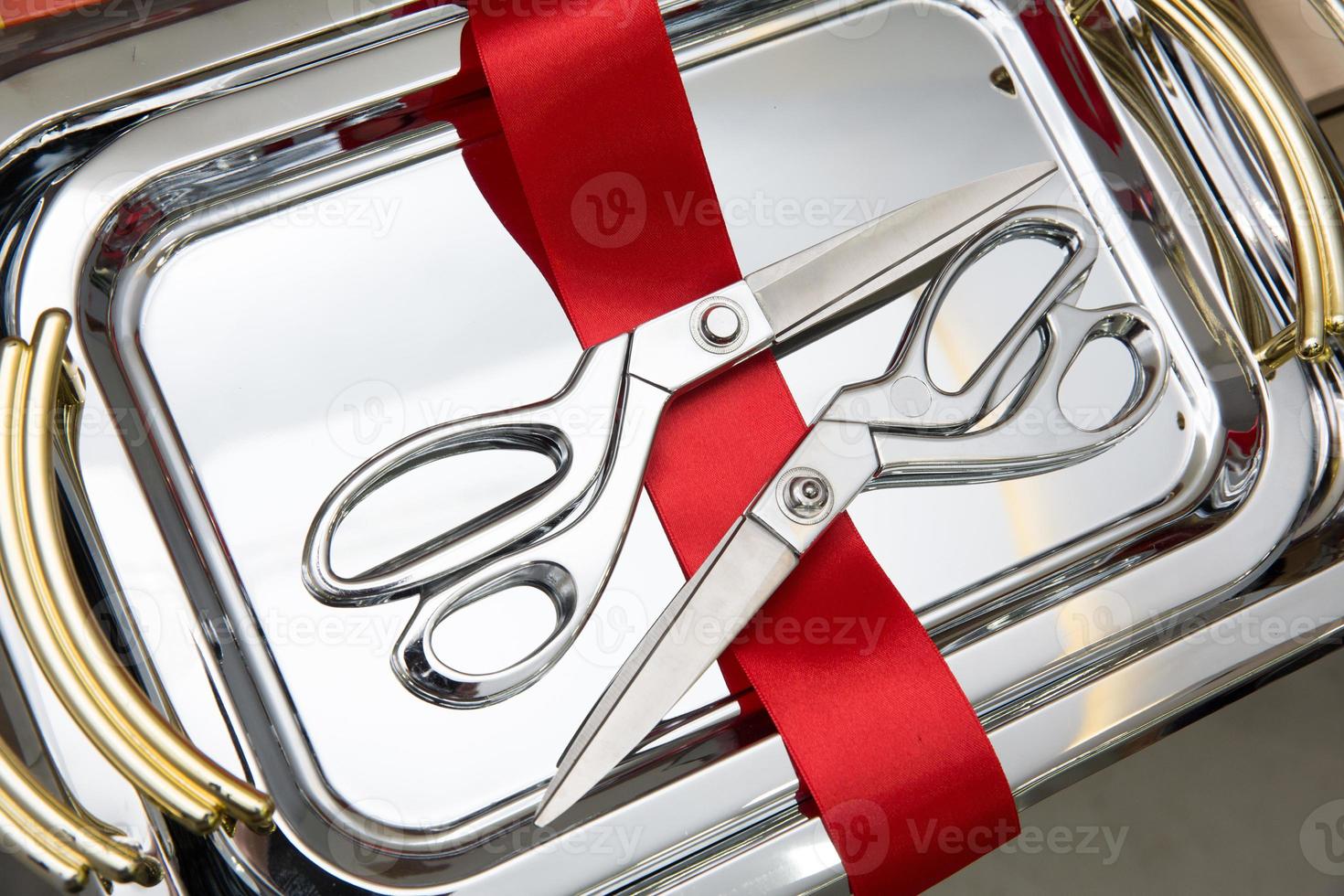 Metal silver scissors used for opening ceremonies with a cut of red tape on a metal tray photo