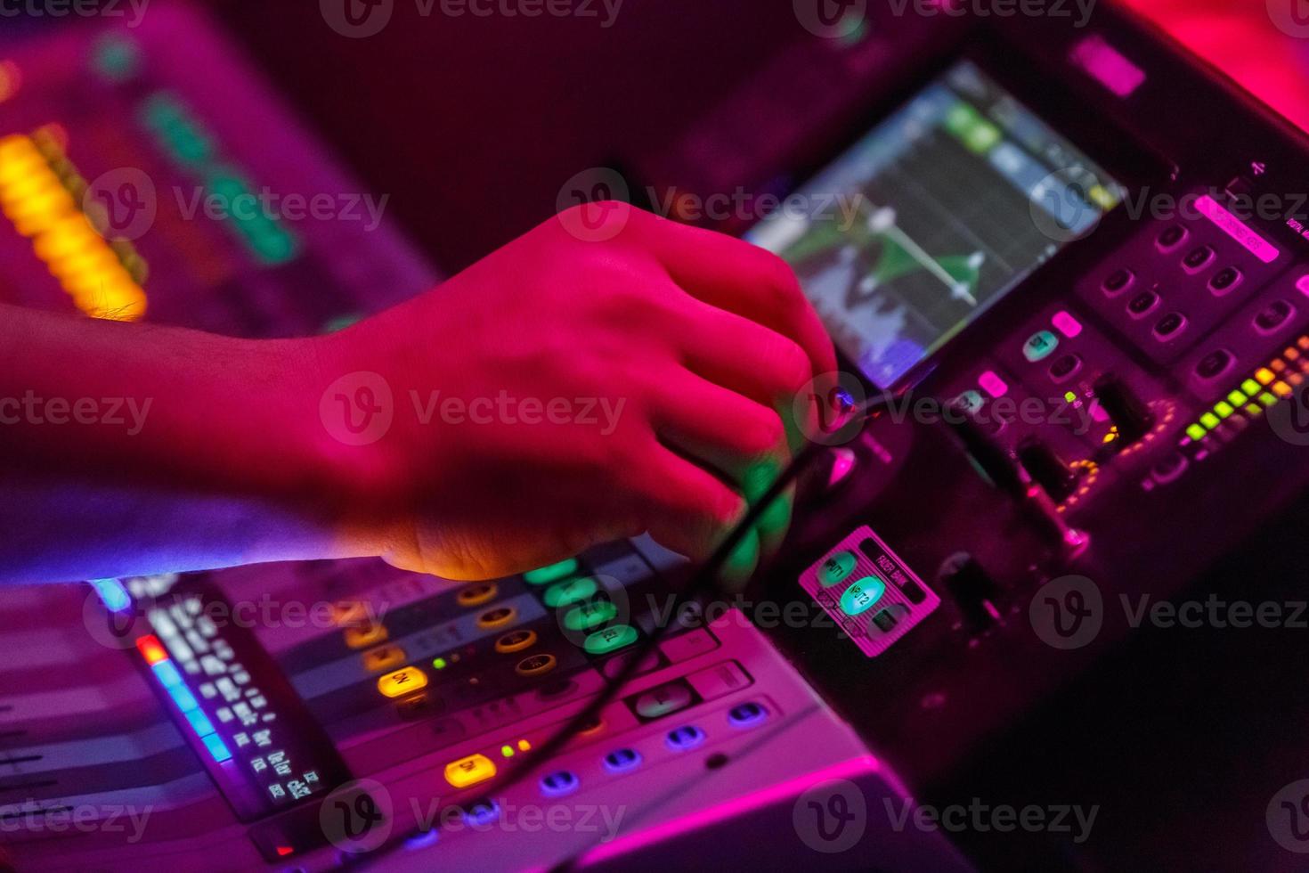 ingeniero de sonido que trabaja con equipos de sonido para conciertos: consola de mezcla de audio y música con botones retroiluminados. foto