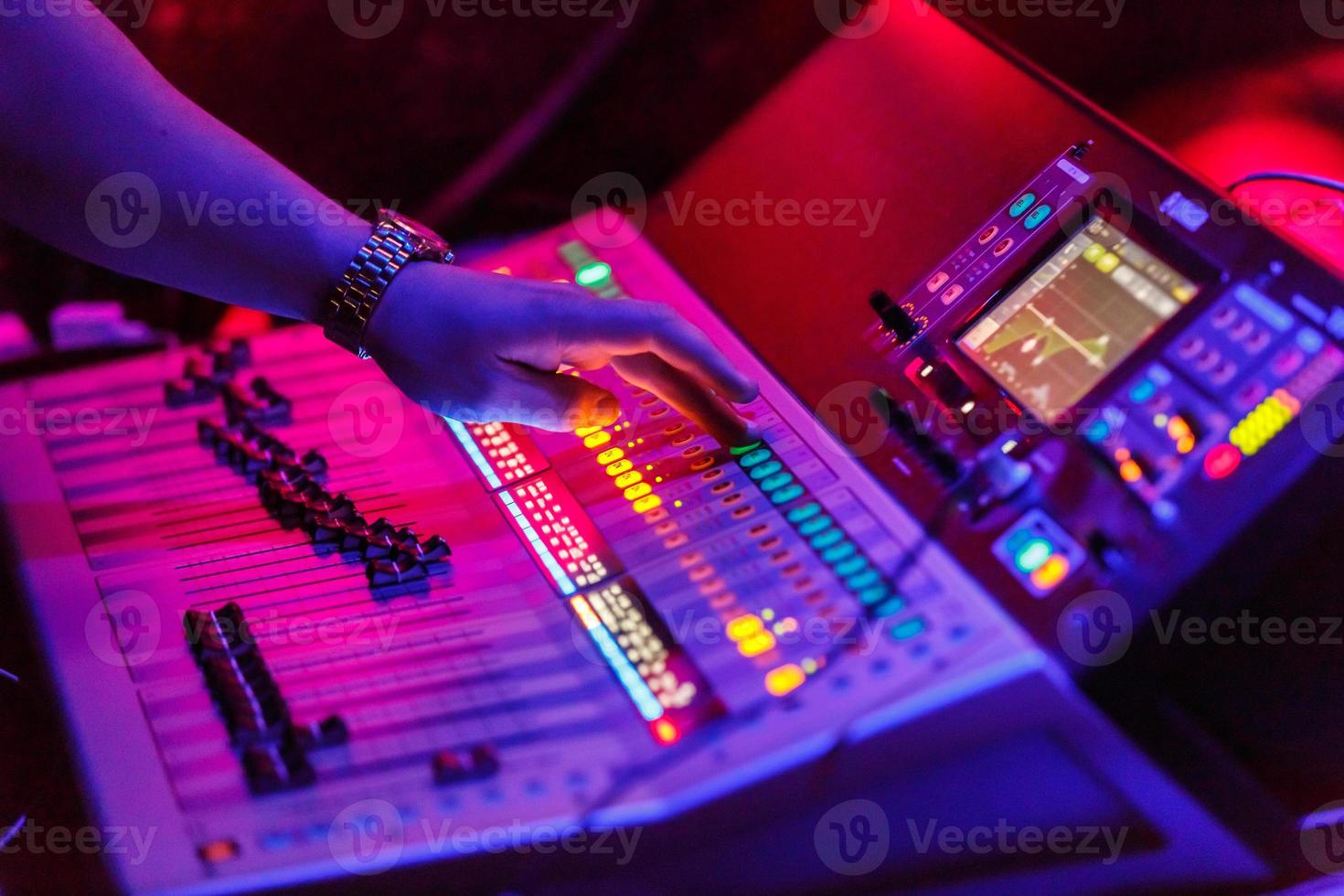 ingeniero de sonido que trabaja con equipos de sonido para conciertos: consola de mezcla de audio y música con botones retroiluminados. foto