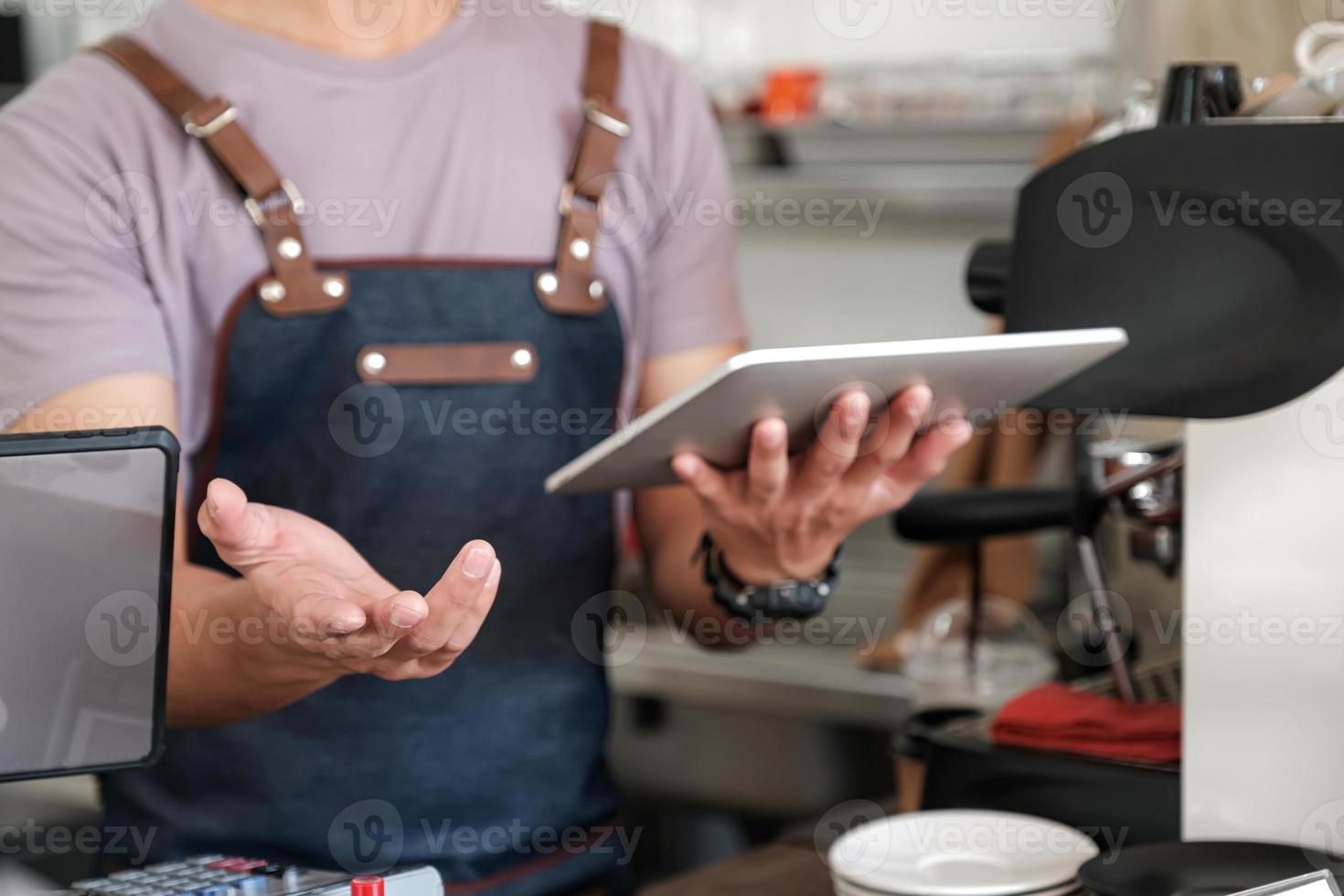 barista holding a tablet in hand, recommending menu and receiving orders from customers. photo